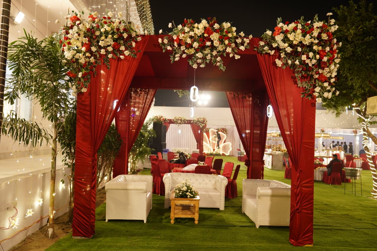 Outdoor lawn lounge under red flower canopy arch