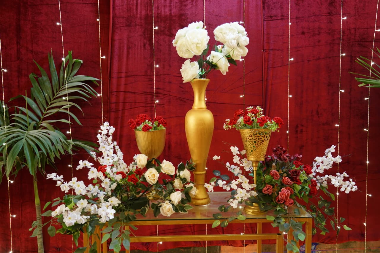 Gold vase floral arrangement with red velvet backdrop